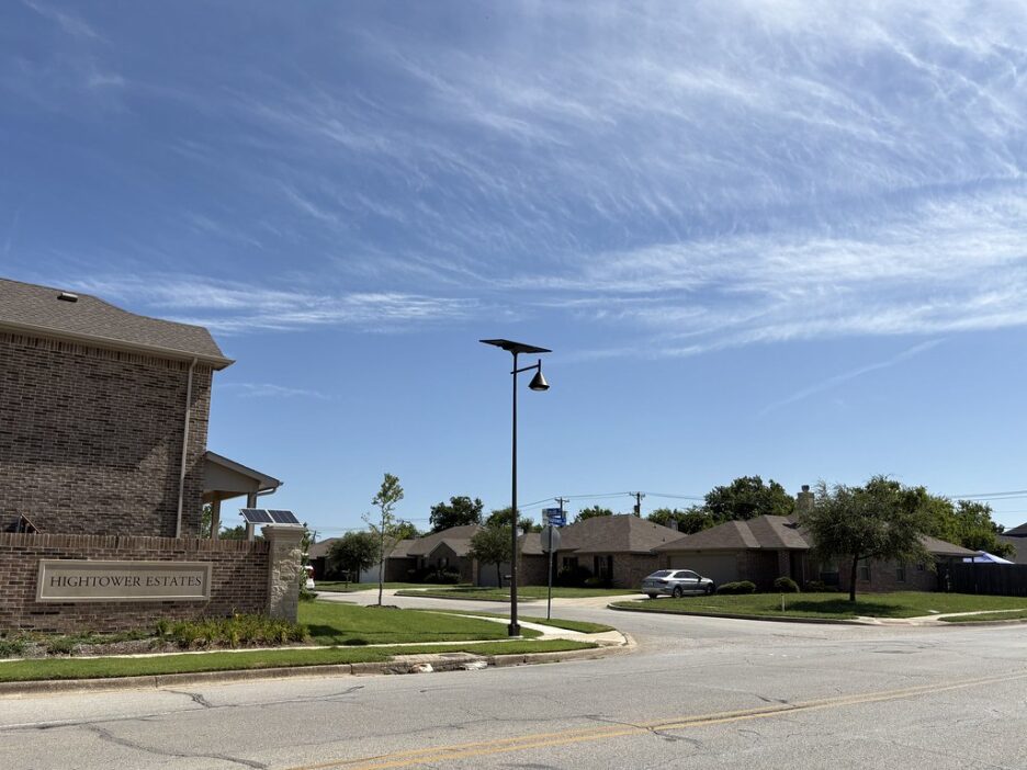 a suburban texas cul de sac lit by sleek solar streetlights in a new housing development.