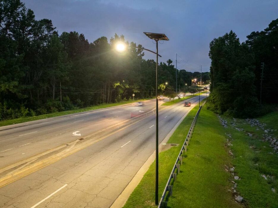 Solar streetlights illuminating a tree-lined roadway in Alabama at dusk, showcasing affordable and resilient off-grid lighting solutions for municipalities.