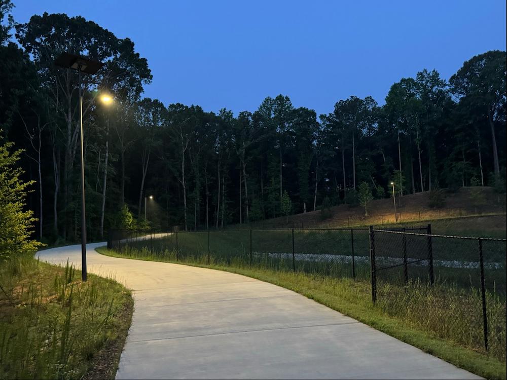 Solar lights illuminating a public walking trail in Alabama at dusk, enhancing visibility and safety in wooded park areas.