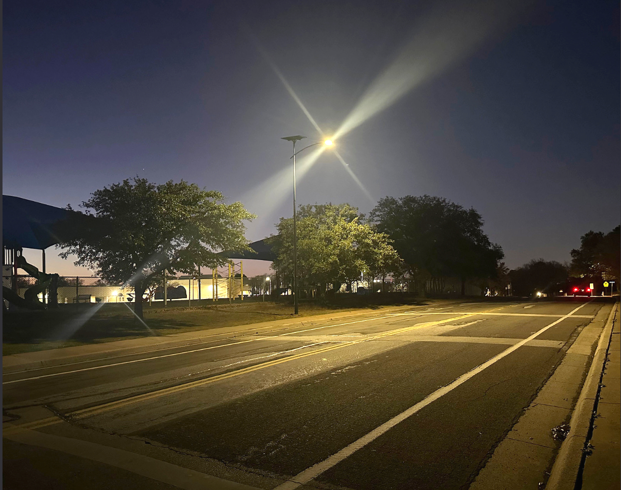 Solar-powered streetlight illuminating a community roadway and park area in Alabama, providing safe and reliable grid-free lighting at night.