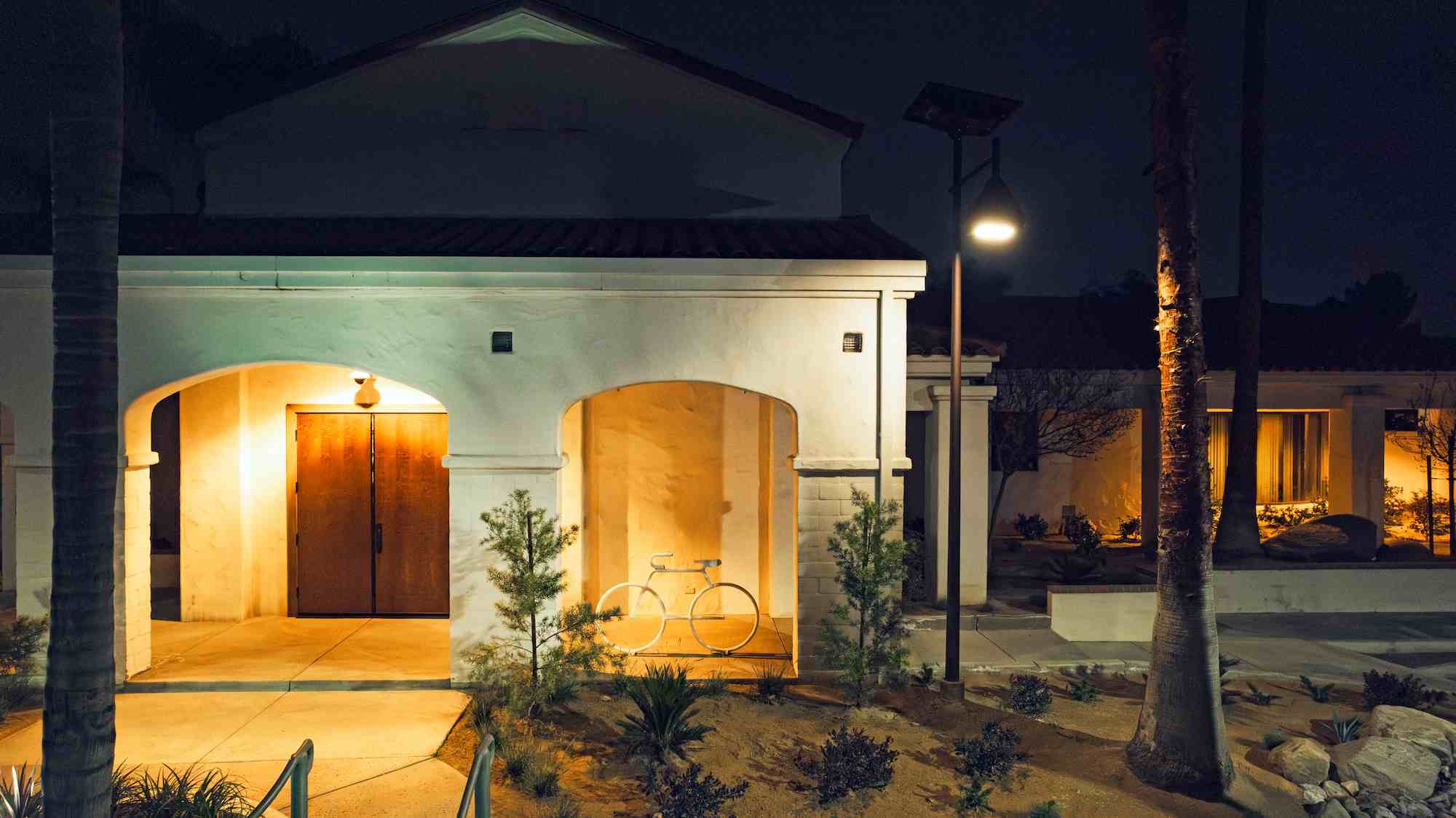 Solar-powered streetlight illuminating the entrance of a California building at night with sustainable lighting