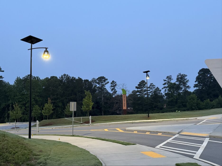 Decorative solar-powered streetlights illuminating a park entrance with no visible wiring or trenching