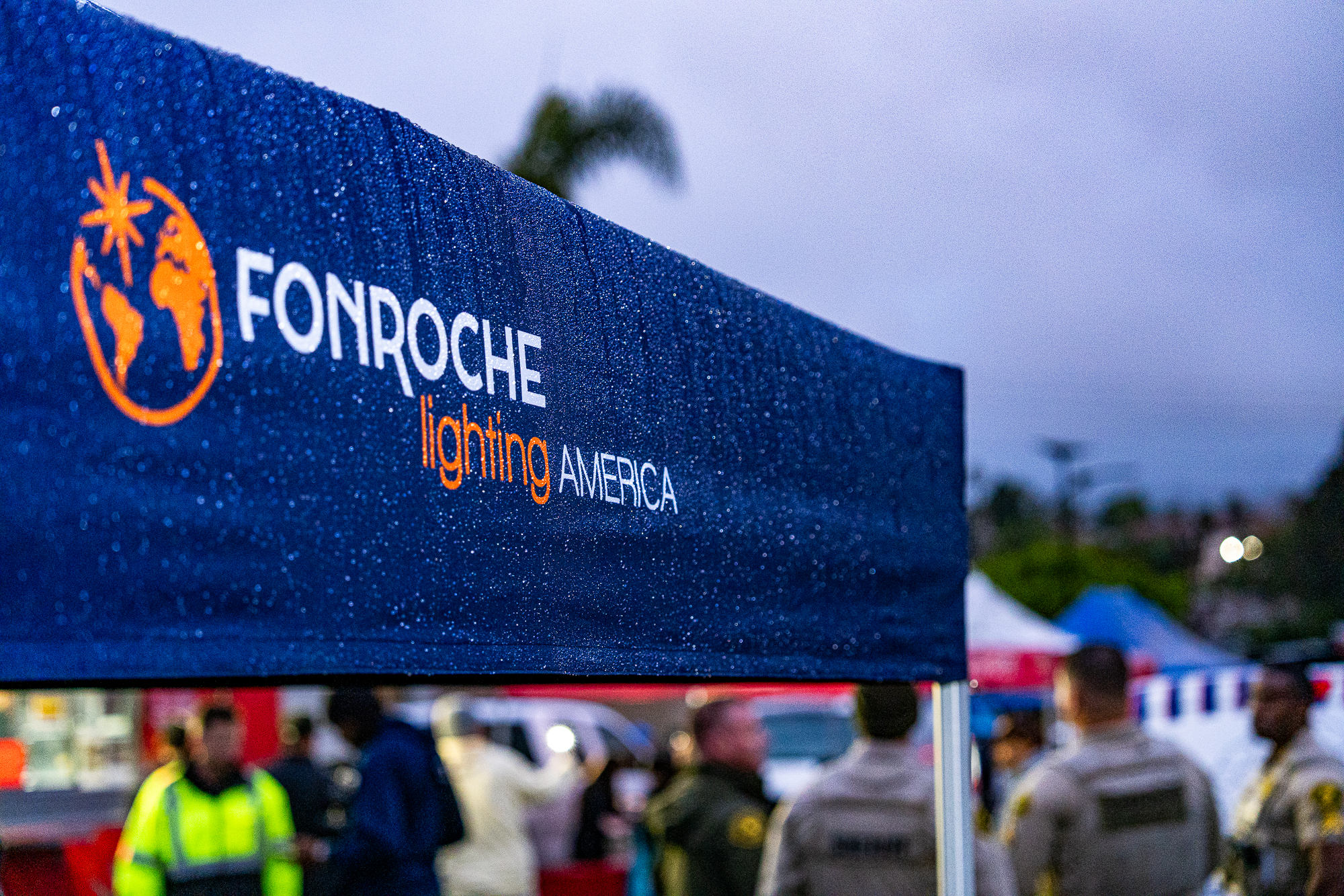 Fonroche Lighting America event canopy with logo visible during a community outreach or emergency response event, attended by uniformed personnel and first responders.