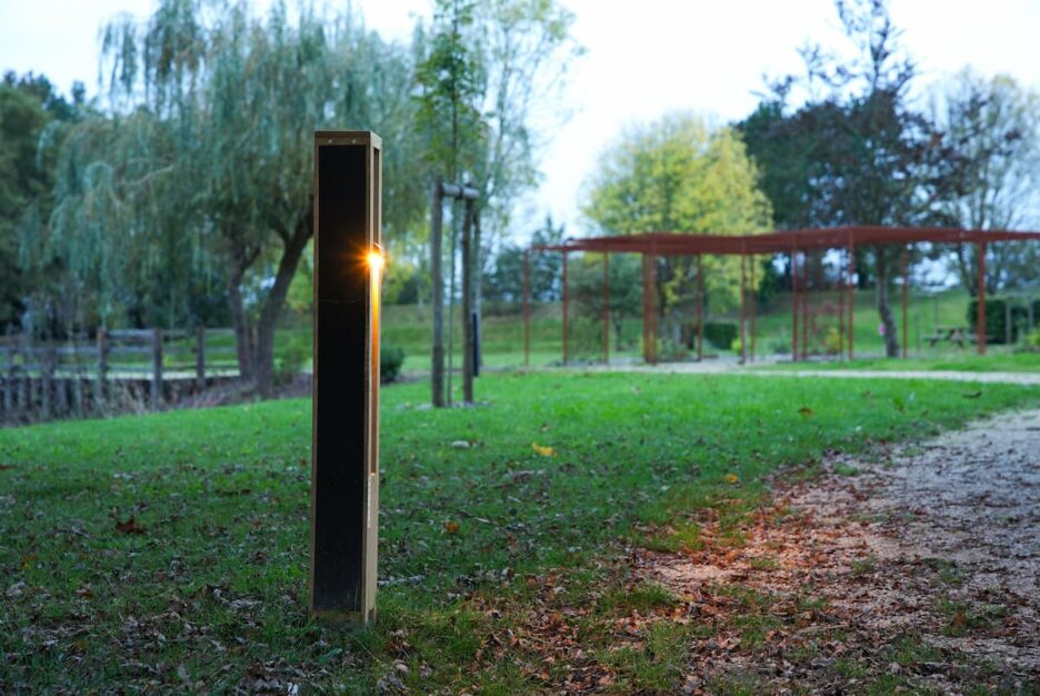 Solar-powered bollard light illuminating a park pathway at dusk, providing safe and sustainable off-grid lighting.