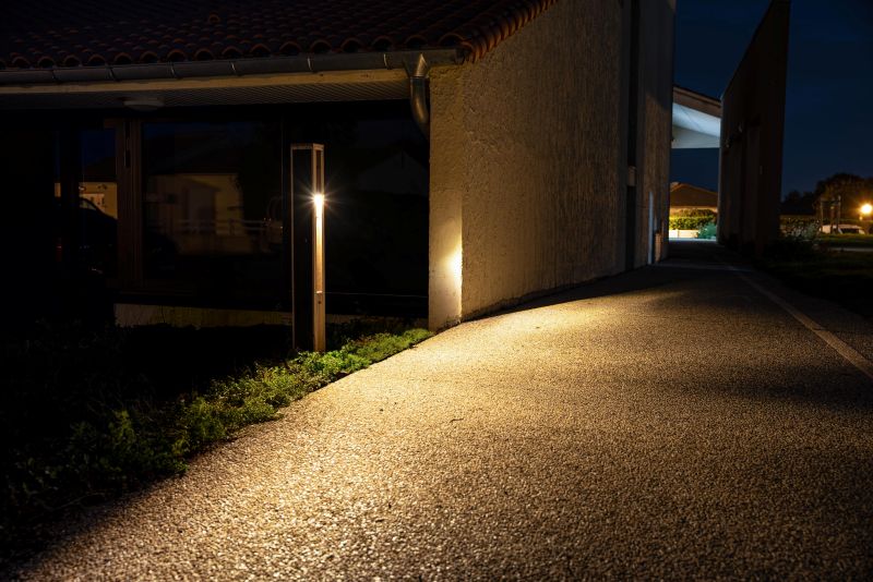 Solar bollard light illuminating a pathway beside a building at night for safe, off-grid access.