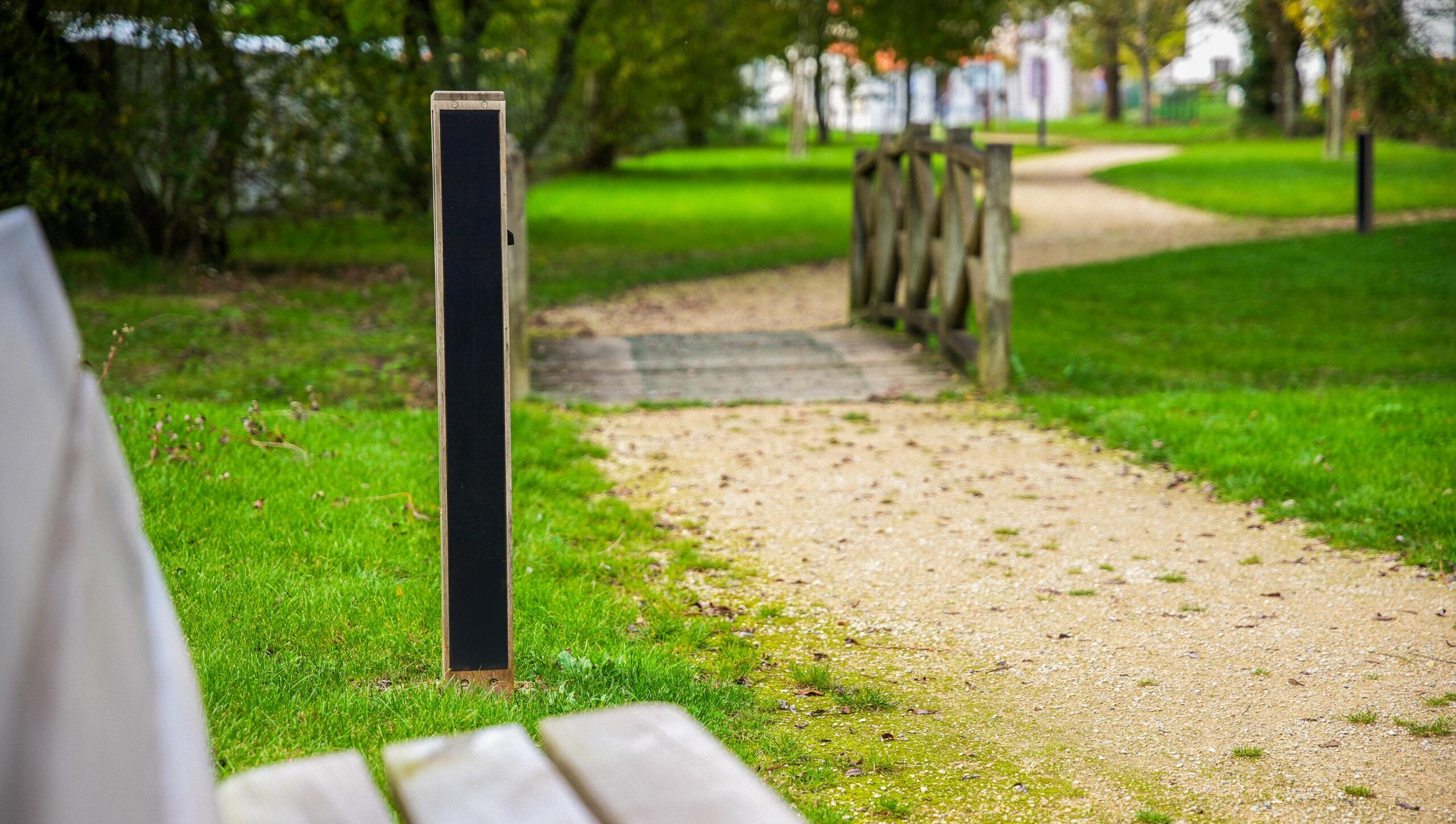 NOWATT solar bollard installed beside a park pathway and wooden bridge, providing sustainable, low-profile lighting for community green spaces and pedestrian access.