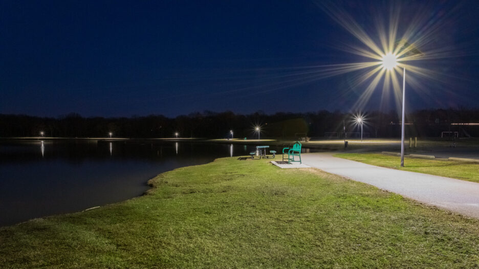 A solar-powered streetlight illuminates a public park and walking path at night in South Carolina, enhancing visibility and safety along waterfront recreation areas.