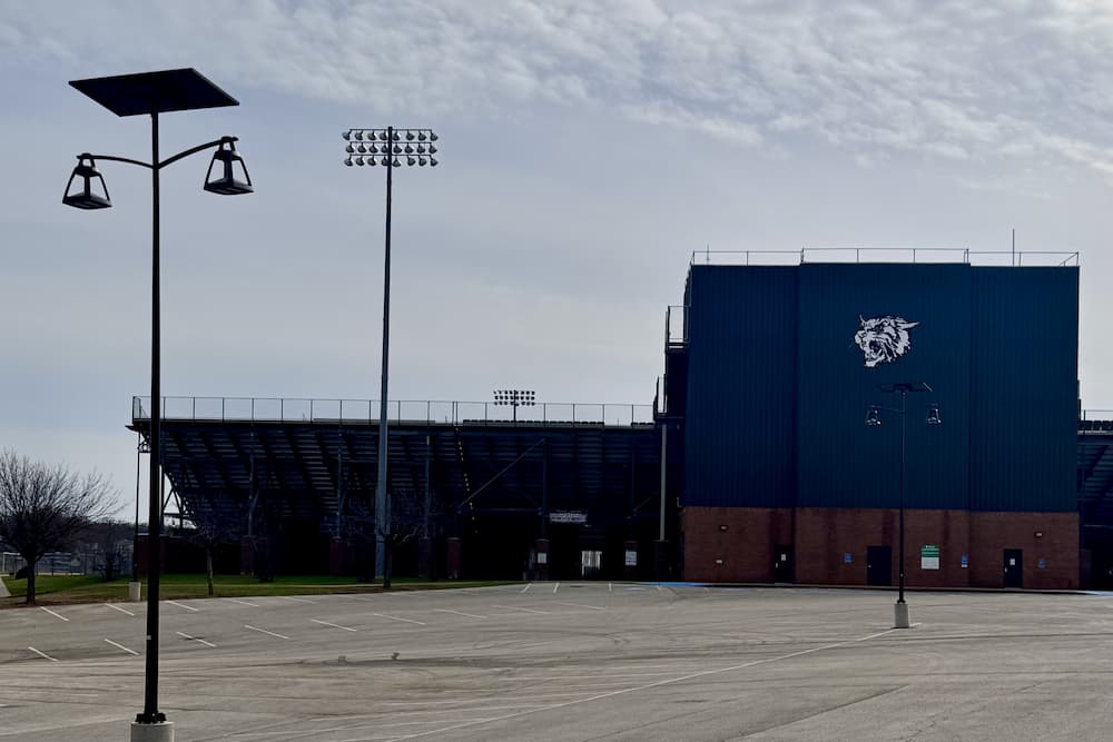 Solar-powered streetlights illuminating a school parking lot in front of a football stadium, enhancing safety and energy efficiency.