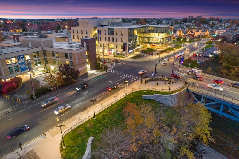 Aerial view of solar streetlights illuminating a busy urban intersection and pedestrian path at sunset, improving visibility and safety