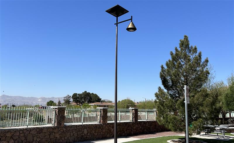 solar street light beside walking path and wooden bridge in a grassy park under a blue sky in Georgia 